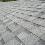 Grey roofing shingles lit by sunlight. ATTYX Roofing