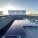 a row of solar panels atop a flat roof.