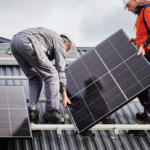 Two solar technicians installing solar panels on the roof of a home.